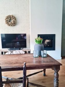 Strakke haard houten salontafel kruik met tulpen krans muur