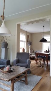 Landelijke salontafel fauteuil met grijze hoes kruik op zuil ombouw doorgang kamer keuken
