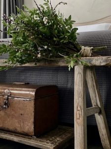 Groene toef op landelijk houten bankje achter het bed oude koffer