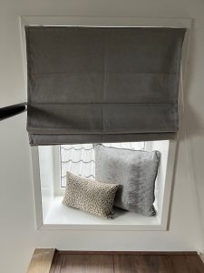 Vouwgordijn donkergrijs kussens in nisje vensterbank