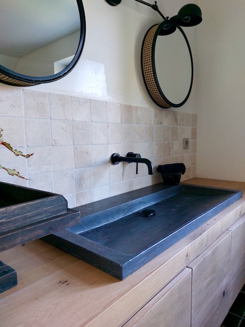 Badkamer landelijke stijl wasbak rechthoek riviersteen ronde spiegels zwarte inbouwkranen badkamer half tegel half stuc