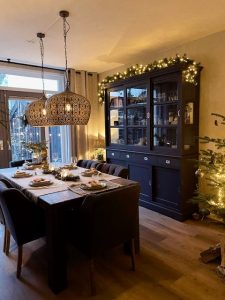Kerst verlichting bovenop landelijke donkergrijze kast koollampen boven gedekte eettafel landelijke stijl