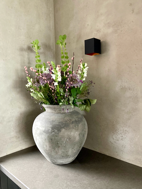 Landelijke kruik met boeket met wit en paarse bloemen zwarte vierkantige spot hoekje aanrecht kalkverf keuken muur