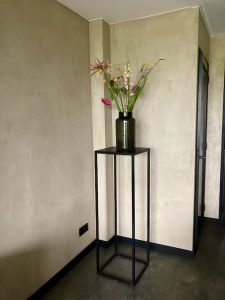 Plantenzuil met zwarte vaas kalkverf muur boeket bloemen landelijk interieur