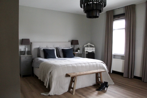 Slaapkamer landelijke stijl Hoffz staafjeslamp houten bankje achter het bed taupe sprei linnen beddengoed