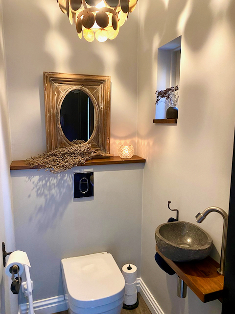 Gestucte muren toilet landelijk ingericht houten plank schijfjeslamp waskom op houten plank dadeltak