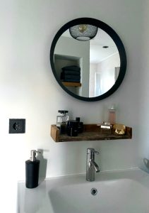 Ronde spiegel houten plankje boven wastafel badkamer zwart stopcontact