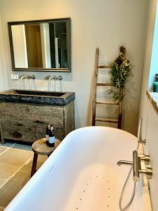 Losstaand wit bad in landelijke badkamer houten decoratieladder badmeubel stoer hout spiegel houten rand