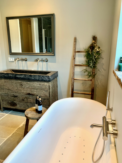 Losstaand wit bad in landelijke badkamer houten decoratieladder badmeubel stoer hout spiegel houten rand