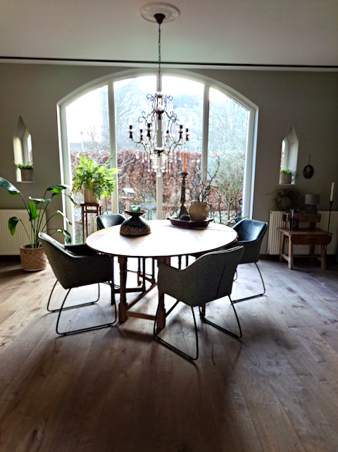 Ronde eethoek boograam woonkamer kroonluchter van glas groene eetkamerstoelen modern