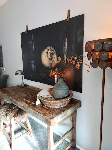 Schijfjeslamp vloerlamp linnen wanddoek met schaap houten werktafel kruk met vachtje olijfbak met landelijke vaas met takken bureaulamp landelijk