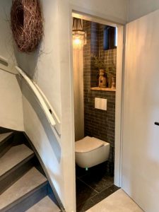 Steentjes muur landelijk toilet grote krans trap opgang grijze trap landelijke ijzeren kroonluchter wc