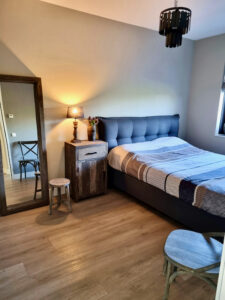 Slaapkamer landelijke stijl grote spiegel met houten rand nachtkastje steigerhout houten krukje metalen hanglamp schijfjes