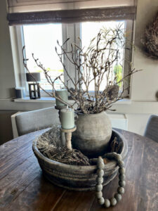 Grote olijfbak woonketting grijze kruik met magnolia takken LED stomp kaarsen grijs op houten kandelaars