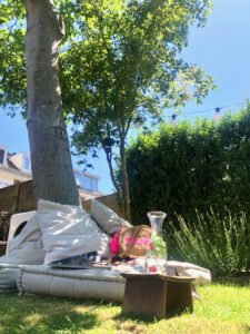 Kussens onder boom in stadstuin water met fruit rotan tas met roze tekst tijdschrift en zonnebril