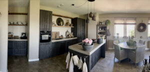 Appartement landelijk ingericht Barnwood kitchen antraciet linnen landelijke eetkamerstoelen taupe vouwgordijnen open keuken