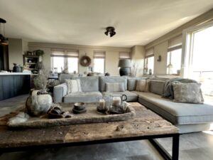 Woonkamer appartement landelijk ingericht grote hoekbank met loungegedeelte kruiklamp met grijze kap