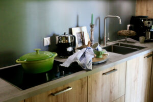 Houten keuken in appartement achterwand muurverf groene pan krans op taarplateau