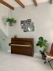 Piano woonkamer witte vloer fotomuur zwart wit hangplant aan balkenplafond