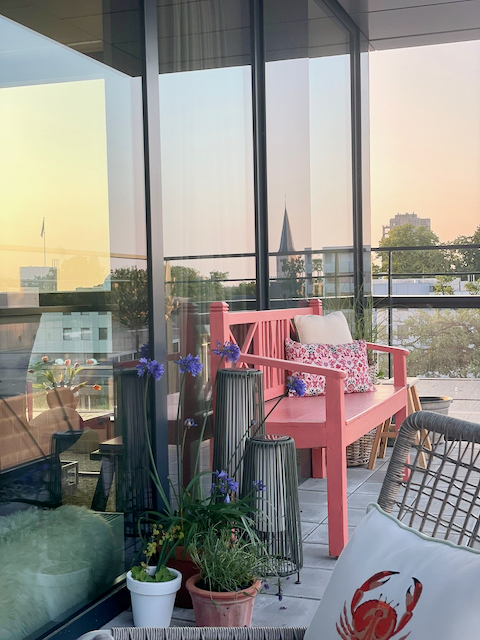 Roze tuinbankje op het balkon hoge windlichten kussen met krab gebloemd sierkussen