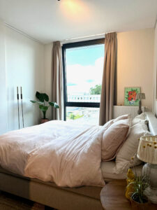 Slaapkamer landelijk strak hoge vloerkandelaars Riviera Maison lampenkap op kruikje wijntafel naast het bed