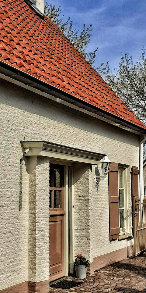 Cottage woning witte steen voordeur met afdak ramen met luiken