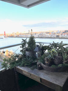 Houten tafeltje met kerstgroen op balkon van appartement ingericht in landelijke stijl