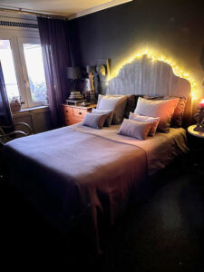 Slaapkamer landelijk sober kerstverlichting achter houten hoofdbord bed